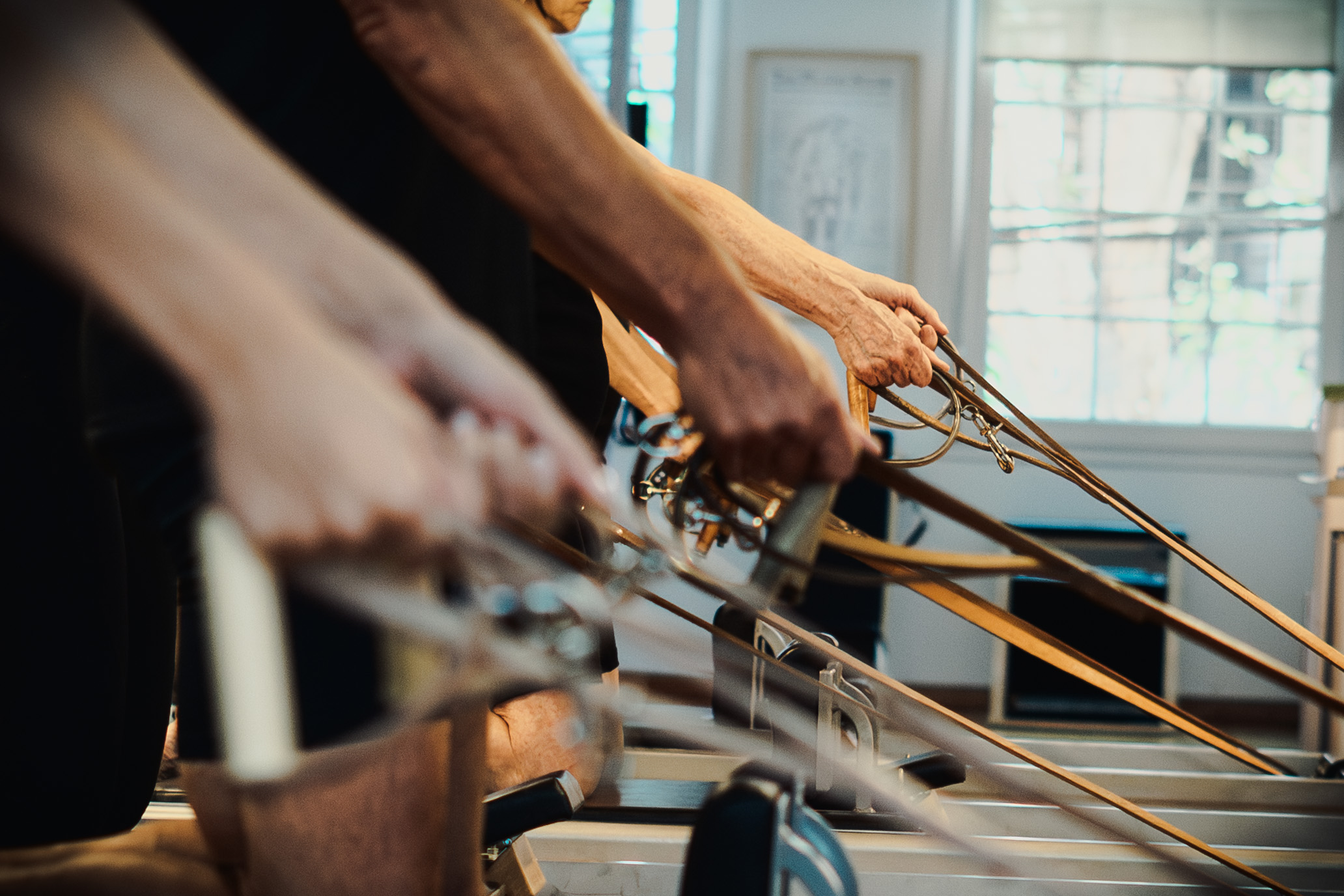 Detalle de manos en las correas del Reformer, estudio Jano Auténtico Pilates
